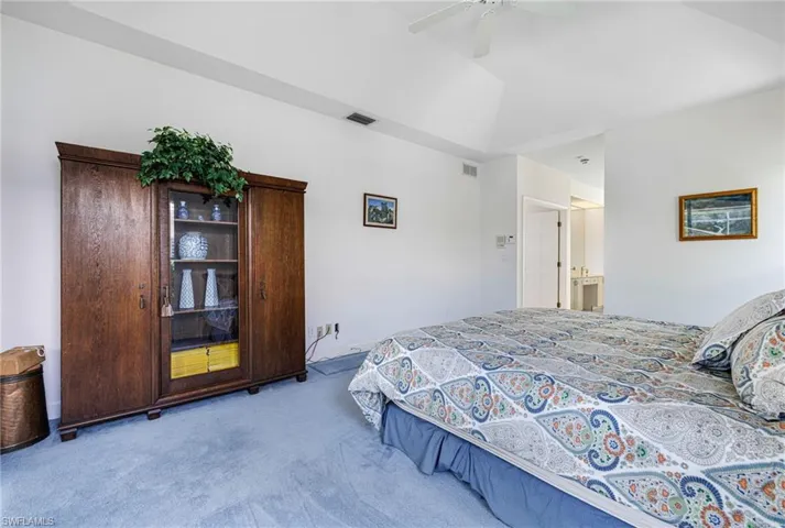 Bedroom with lofted ceiling, visible vents, carpet floors, and ceiling fan