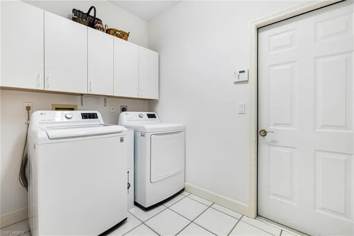 Laundry area with cabinet space, washer and dryer, baseboards, and light tile patterned flooring