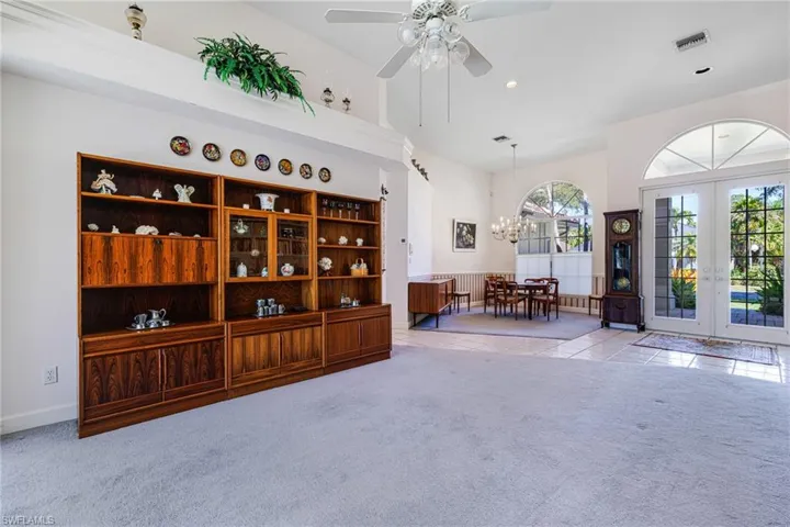 Sitting room featuring visible vents, carpet floors, ceiling fan with notable chandelier, french doors, and tile patterned floors