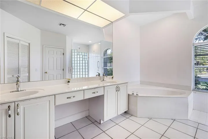 Full bathroom featuring visible vents, tile patterned floors, double vanity, a bath, and a sink