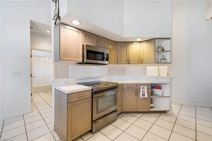 Kitchen featuring baseboards, open shelves, light tile patterned flooring, stainless steel appliances, and light countertops