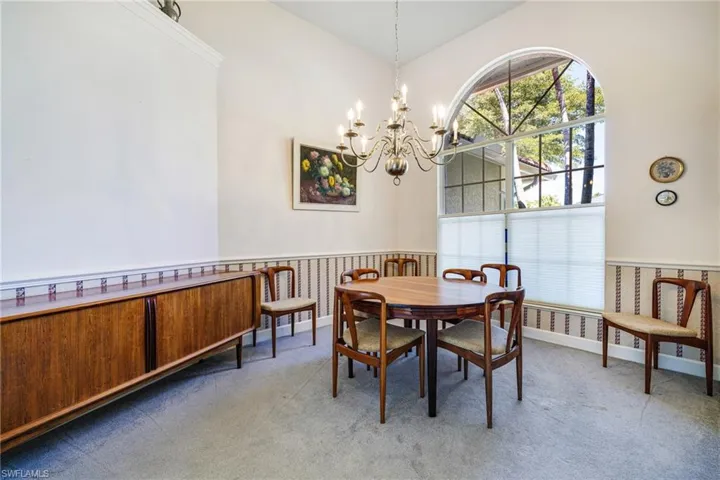 Carpeted dining space with a notable chandelier and wainscoting