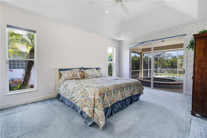 Carpeted bedroom featuring a ceiling fan, baseboards, wallpapered walls, lofted ceiling, and access to outside