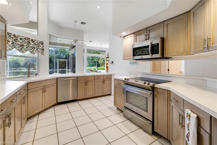 Kitchen featuring ceiling fan, light countertops, a peninsula, stainless steel appliances, and a sink
