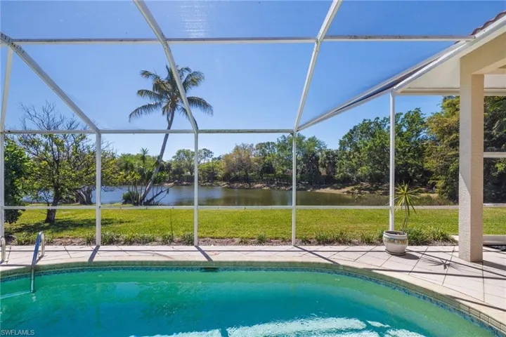 Outdoor pool with a lanai, a lawn, a patio, and a water view