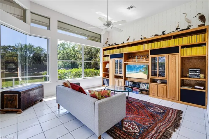 Living area featuring light tile patterned flooring, visible vents, wallpapered walls, and ceiling fan