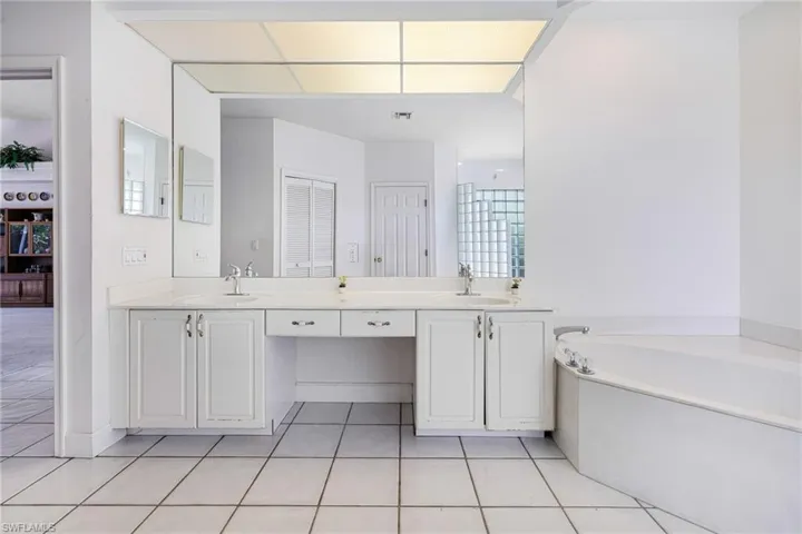 Bathroom with tile patterned flooring, a garden tub, double vanity, and a sink