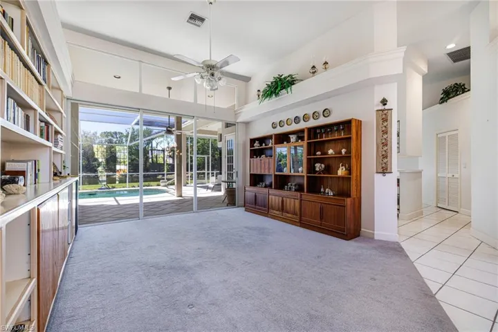 Unfurnished living room with tile patterned floors, visible vents, a towering ceiling, a sunroom, and ceiling fan