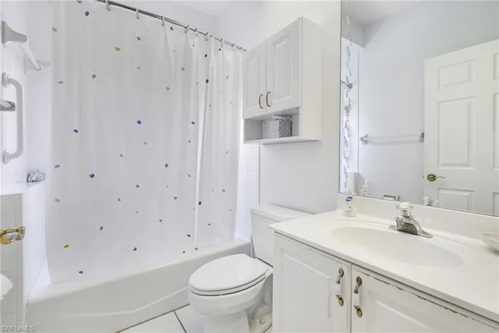 Full bathroom with tile patterned flooring, toilet, vanity, and shower / bath combo