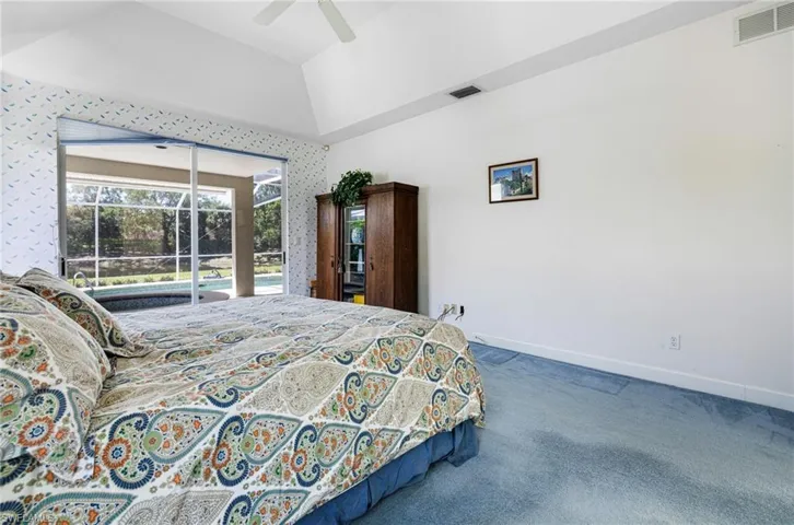 Carpeted bedroom with vaulted ceiling, baseboards, visible vents, and ceiling fan