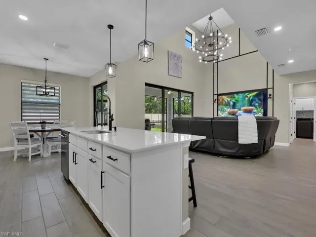The open concept living area features a kitchen island with white cabinetry, sink, and pendant lighting