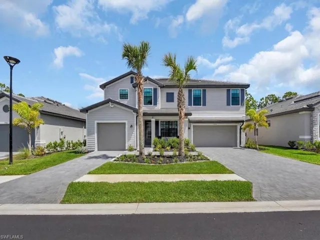 Two story exterior with 2 garages, large paved driveway, palm trees and manicured lanscaping