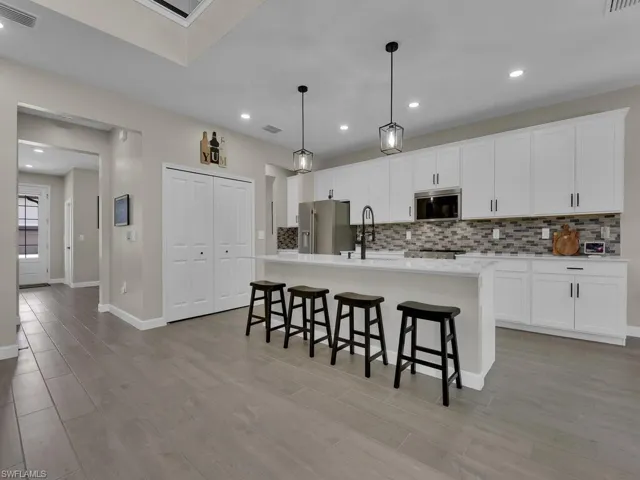 Kitchen featuring white shaker cabinets, white quartz countertops, large island with seating and pantry