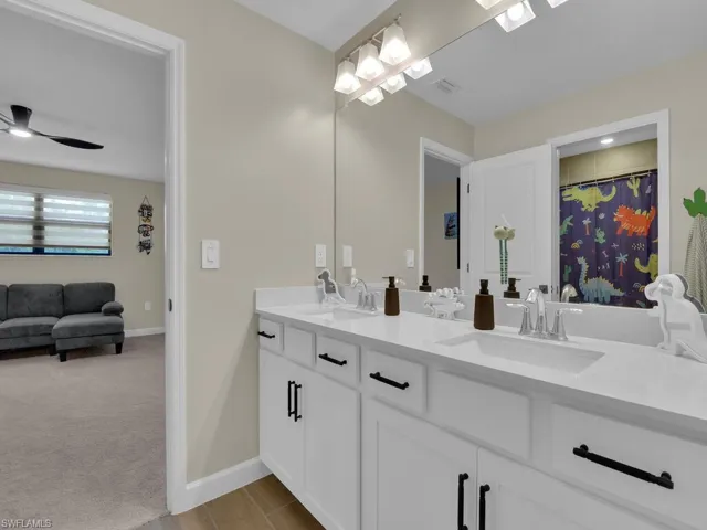 Bathroom with dual sinks, large vanity and separate door for toilet and shower/tub combo