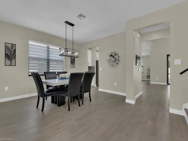 Dining area featuring a modern chandelier, a window with horizontal blinds, and wood-look tile flooring