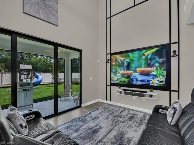 This living area features high ceilings and a large entertainment wall with a mounted screen