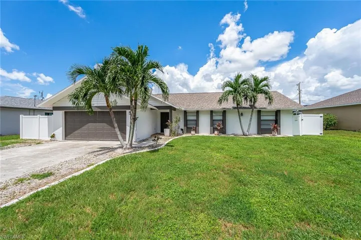 Ranch-style home with driveway, a front lawn, an attached garage, and fence