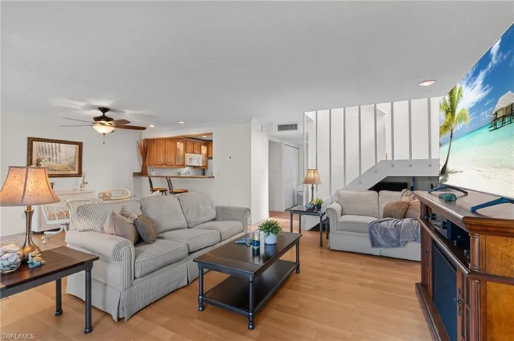 Living room with a ceiling fan, light wood-style flooring, recessed lighting, and a textured ceiling