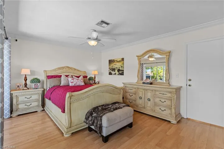 Bedroom with ornamental molding, light wood-style floors, and a ceiling fan