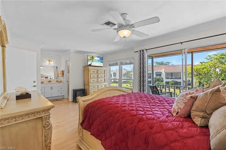 Bedroom with light wood-type flooring, ornamental molding, access to outside, ceiling fan, and ensuite bath
