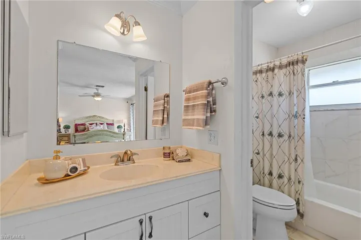 Ensuite bathroom with vanity, shower / tub combo, ceiling fan, and tile patterned floors