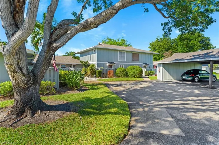 View of front facade with asphalt driveway and a front lawn