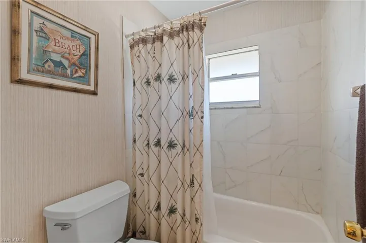Full bathroom featuring shower / tub combo and wallpapered walls