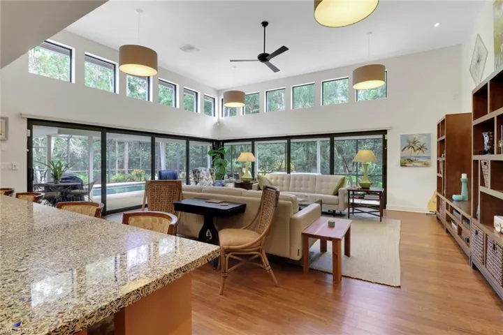 Living area featuring ceiling fan, a towering ceiling, and light wood-style flooring