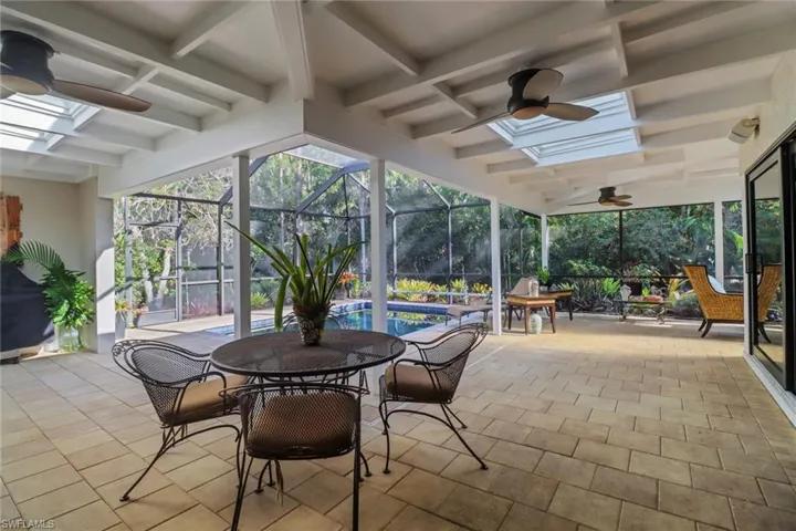 View of patio / terrace with outdoor dining area, ceiling fan, an outdoor pool, and glass enclosure