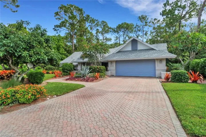Ranch-style home featuring a shingled roof, decorative driveway, a garage, and a front lawn