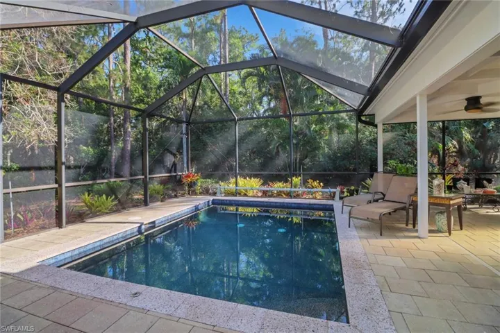 Outdoor pool with a patio area and glass enclosure