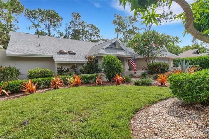 View of front of house featuring roof with shingles, a front yard, and stucco siding