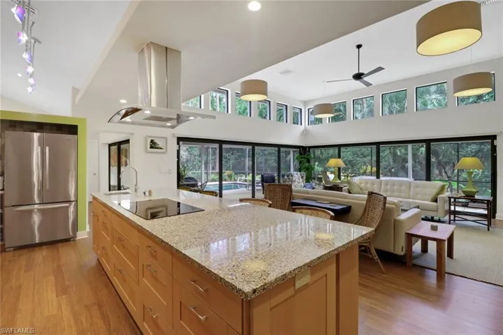 Kitchen with freestanding refrigerator, island exhaust hood, a ceiling fan, light wood-style floors, and plenty of natural light