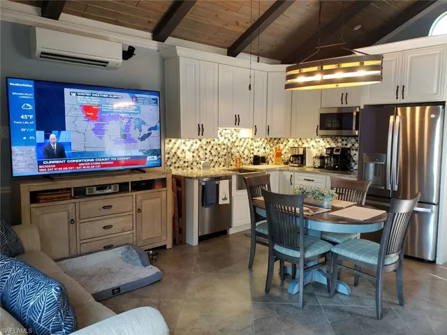 Kitchen featuring wood ceiling, stainless steel appliances, a wall mounted air conditioner, and vaulted ceiling with beams
