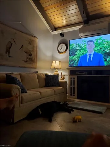 Tiled living room with wood ceiling, beamed ceiling, and a wall unit AC