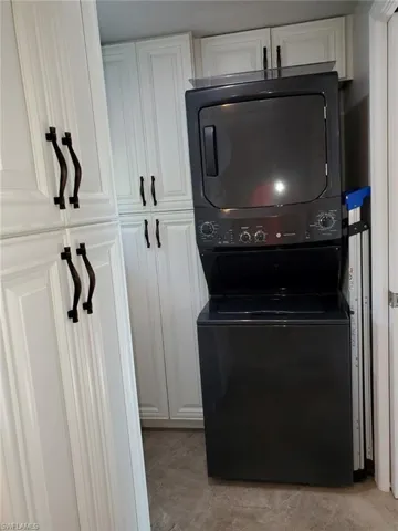 Clothes washing area featuring cabinets and stacked washer / drying machine