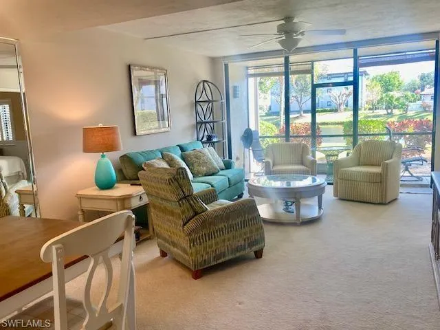 Carpeted living room featuring expansive windows and ceiling fan