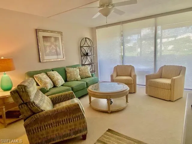 Living room featuring plenty of natural light, ceiling fan, and carpet flooring