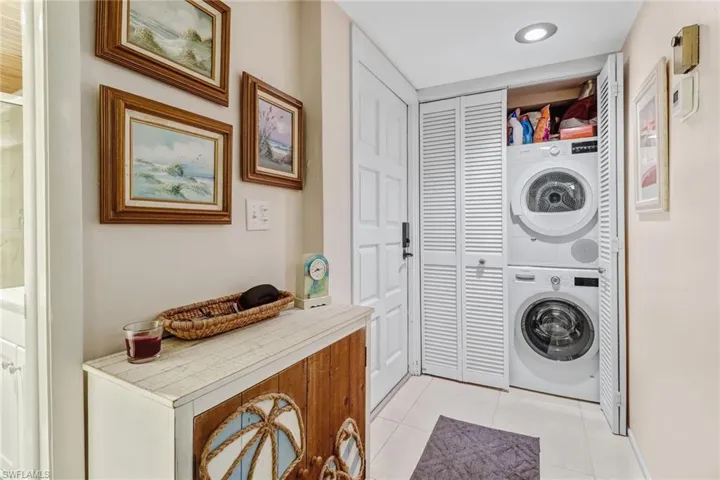 Washroom featuring light tile patterned flooring and stacked washer / drying machine