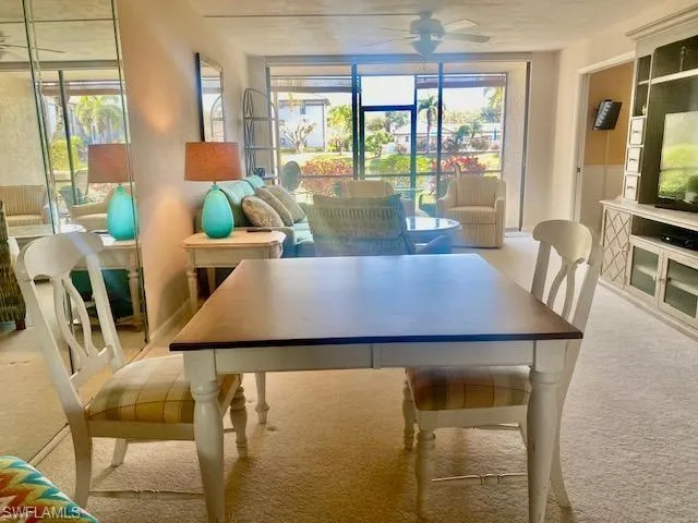 Carpeted dining space featuring a healthy amount of sunlight and ceiling fan