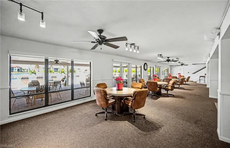 Carpeted dining space with track lighting, ceiling fan, and a water view