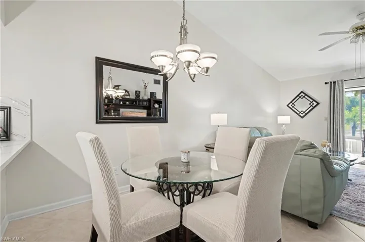 Dining room featuring light tile patterned floors, lofted ceiling, a ceiling fan, and a chandelier