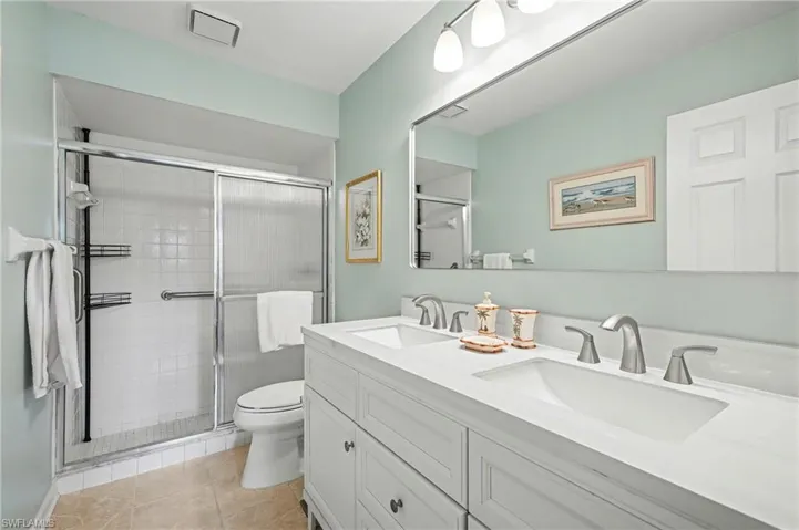 Bathroom with double vanity, a stall shower, and light tile patterned flooring