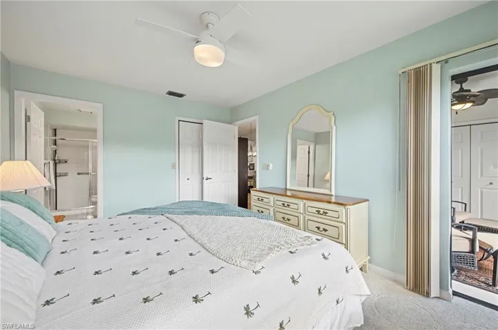Bedroom featuring light carpet, connected bathroom, and a ceiling fan