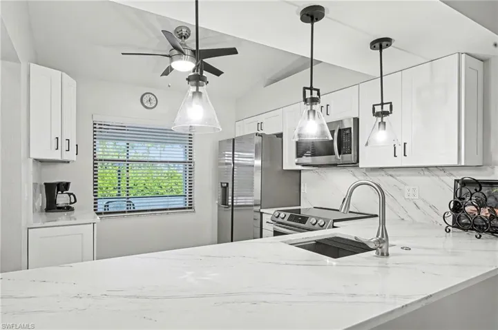 Kitchen featuring light stone countertops and hanging light fixtures