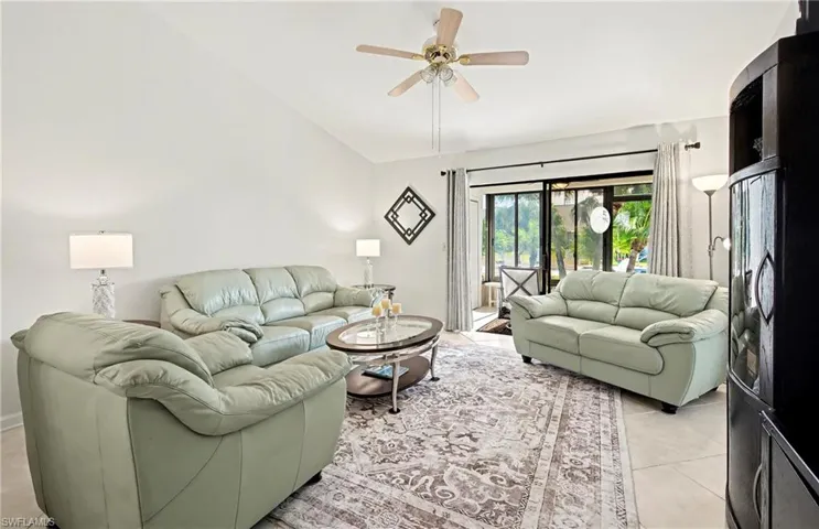Living area featuring vaulted ceiling, light tile patterned floors, and ceiling fan