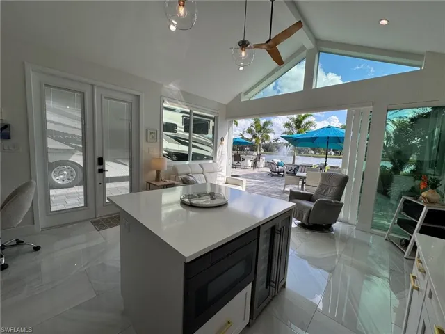 Kitchen featuring a kitchen island, beamed ceiling, ceiling fan, and white cabinets