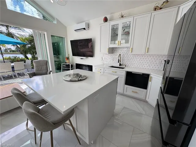 Kitchen featuring a kitchen bar, lofted ceiling, a center island, white cabinets, and sink
