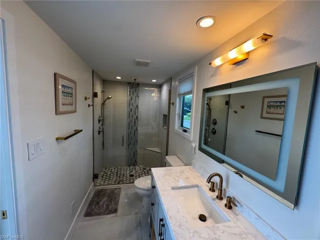 Bathroom featuring vanity, toilet, and a shower with door