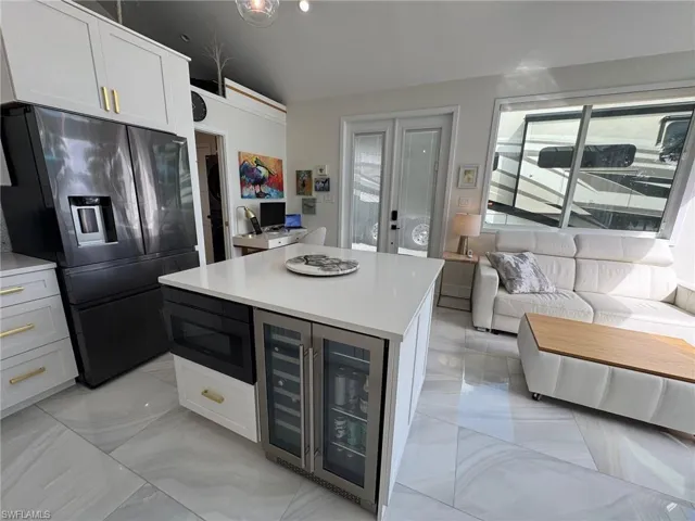 Kitchen with wine cooler, white cabinetry, stainless steel refrigerator with ice dispenser, and built in microwave